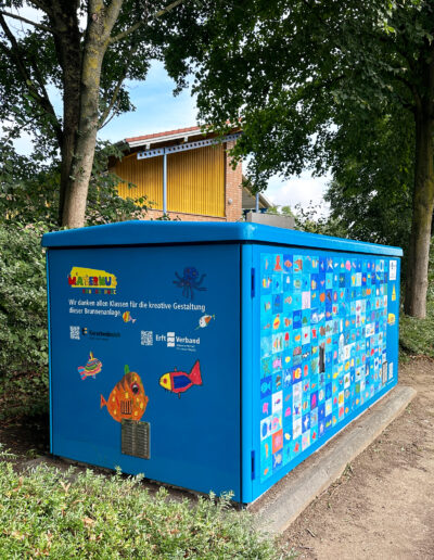 Brunnen wurde von einer Grundschule neugestaltet, bunte gemalte Fische zieren den blauen Brunnen.